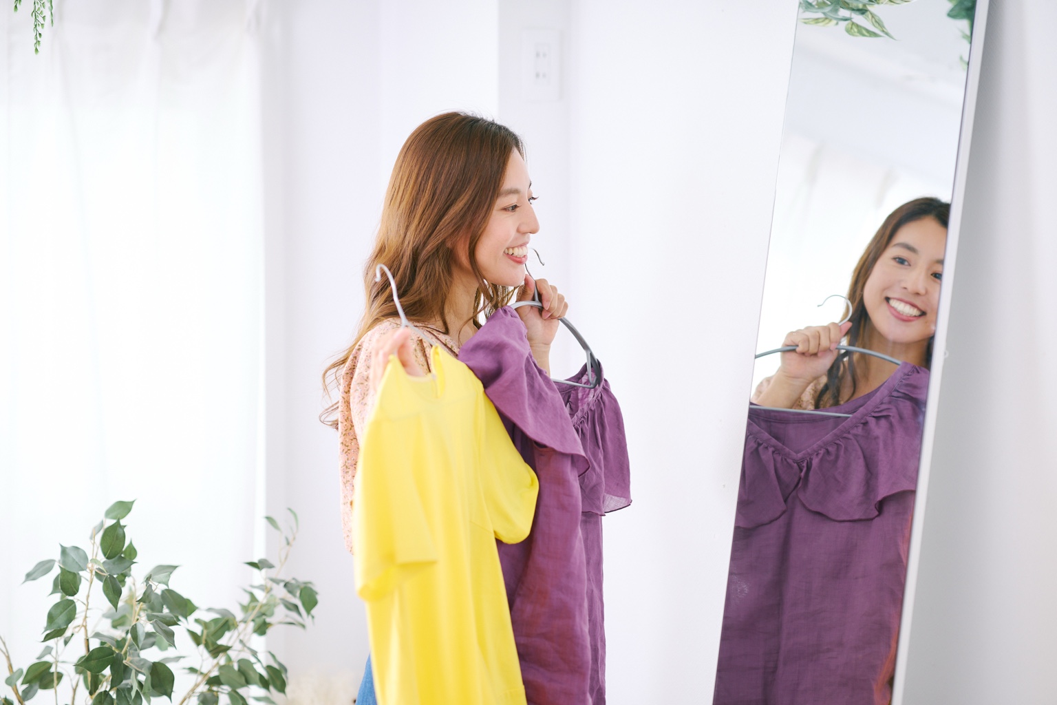鏡の前で紫の洋服を合わせる女性