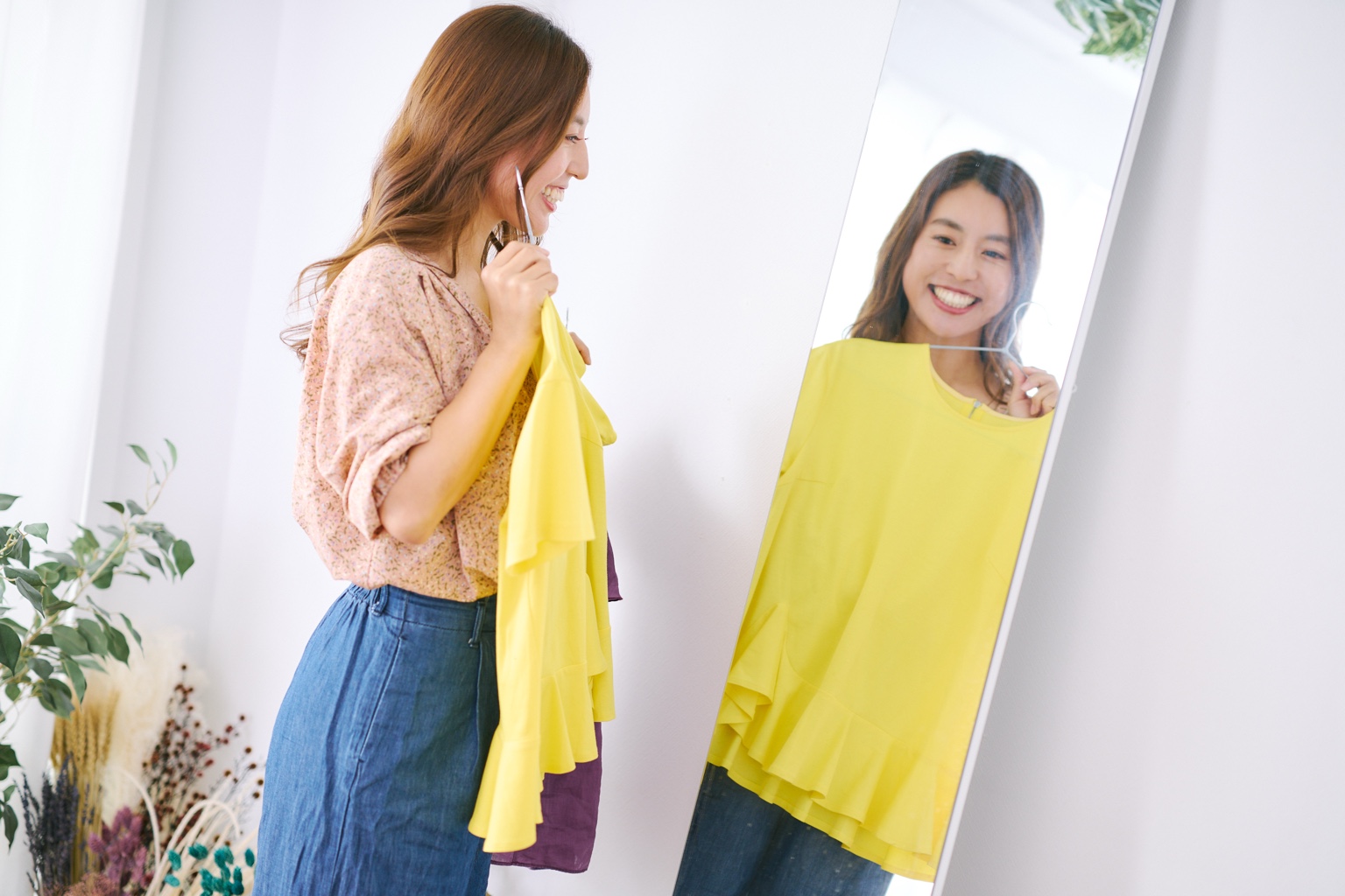 鏡の前で届いた洋服を自分に合わせて楽しむ女性
