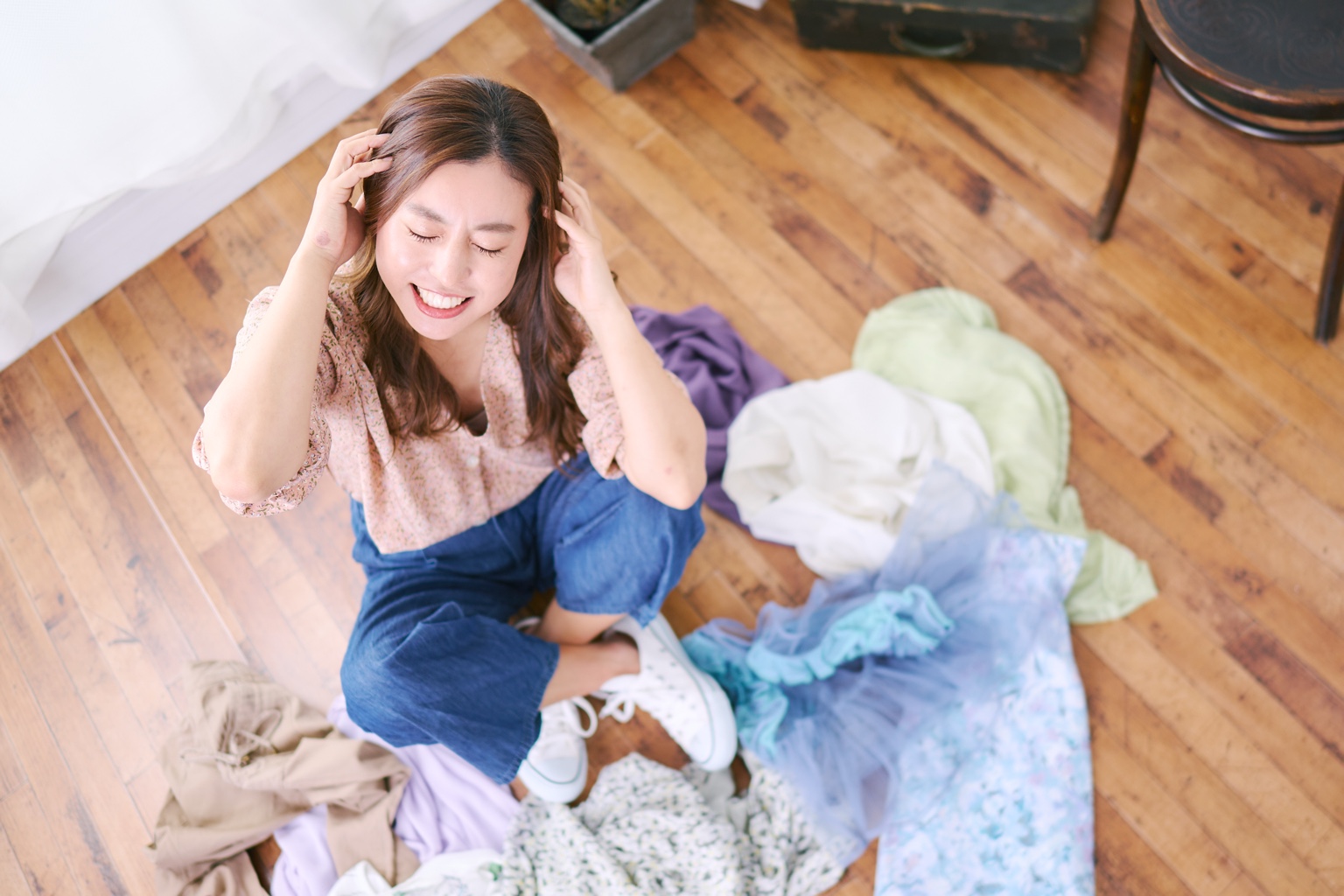 たくさんの洋服を前に何を着るか悩んでいる女性